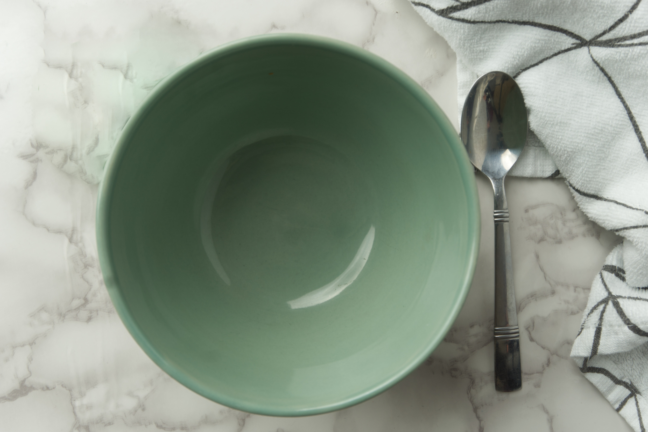 An empty bowl centered in the middle of the image with a spoon on the right